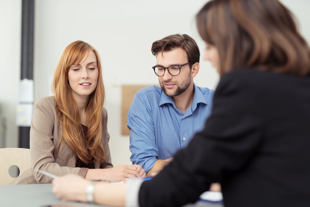 Broker showing a document to young couple