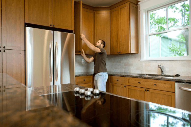 Man inspecting cabinets in kitchen