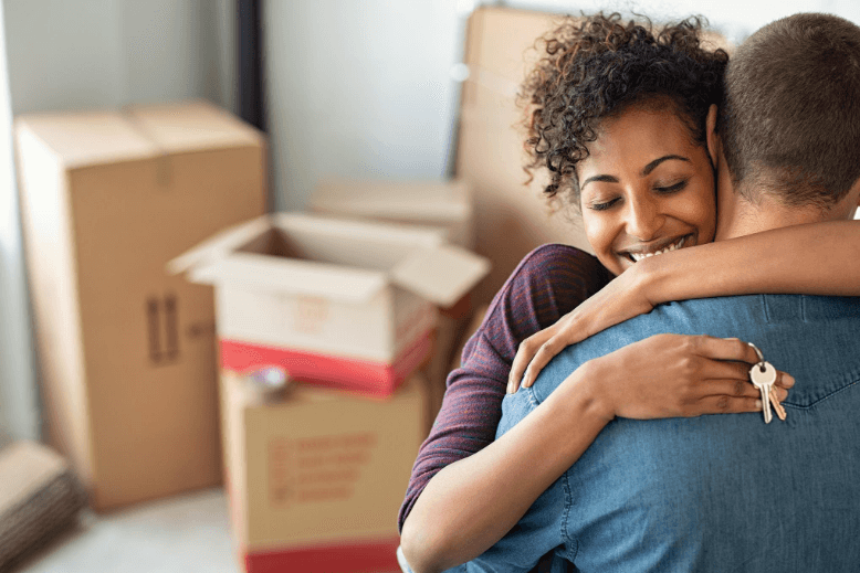 Young woman hugging partner in new home and holding keys