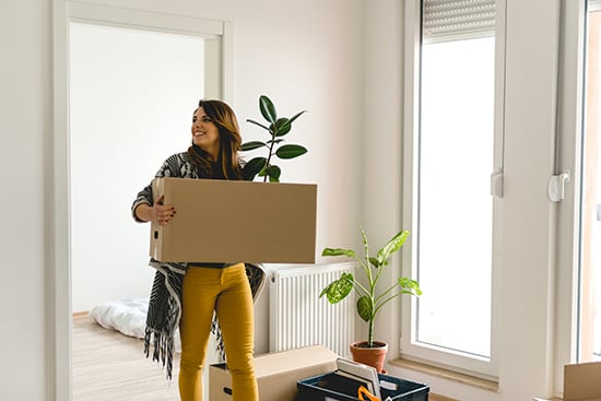 First-time homebuyer carrying box into empty new home