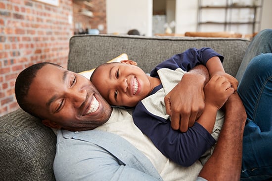 Father and son cuddling together on sofa
