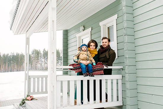 Family standing on porch of rural home in the winter