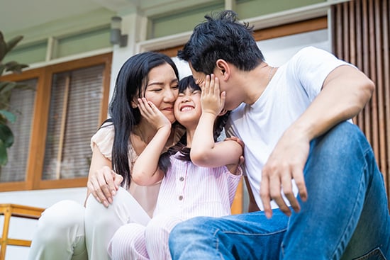 Happy parents with daughter on front porch of their home