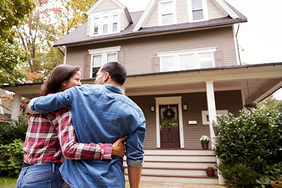 Young couple standing outside their home