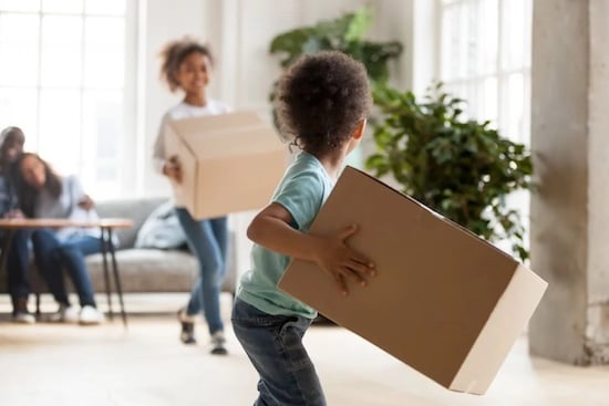 Children running with moving boxes in new home